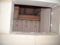 Pohled do topeniště, otvory slouží pro přívod předehřátého vzduchu, který podporuje hoření všech plynných složek dřeva.